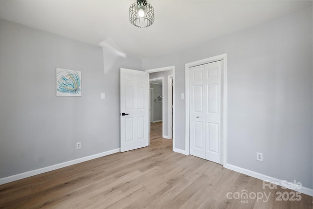 unfurnished bedroom featuring baseboards, a closet, and wood finished floors