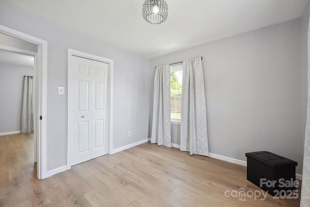 unfurnished bedroom with a closet, wood finished floors, and baseboards