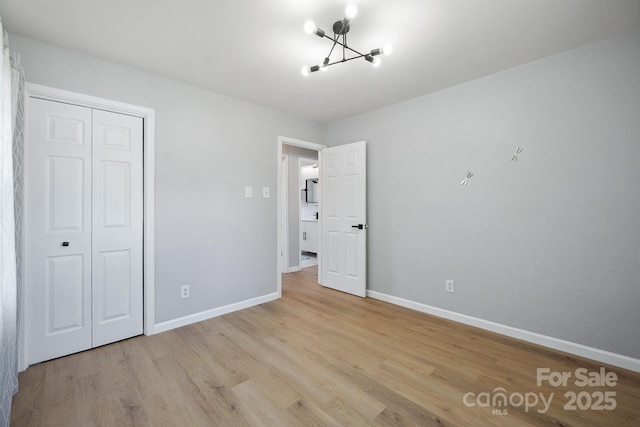 unfurnished bedroom featuring a chandelier, baseboards, a closet, and light wood finished floors