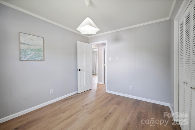 unfurnished bedroom with light wood finished floors, crown molding, a closet, and baseboards