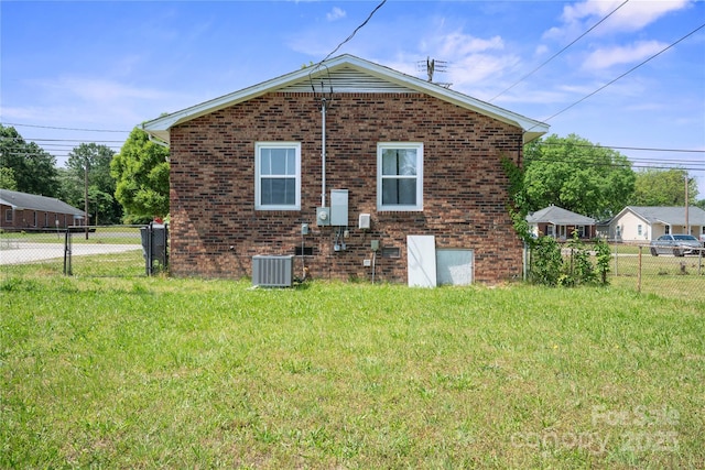 rear view of property featuring central air condition unit, a fenced backyard, brick siding, and a lawn