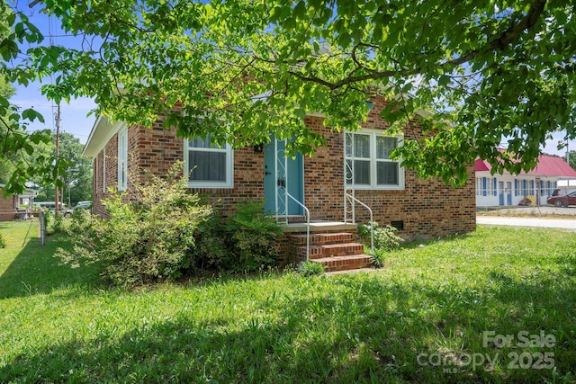 obstructed view of property with a front lawn, brick siding, and fence