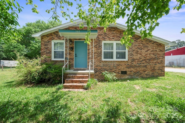 bungalow featuring fence, a front lawn, and brick siding