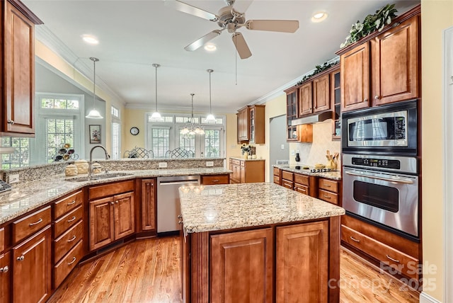 kitchen featuring appliances with stainless steel finishes, a sink, ornamental molding, plenty of natural light, and light wood-style flooring