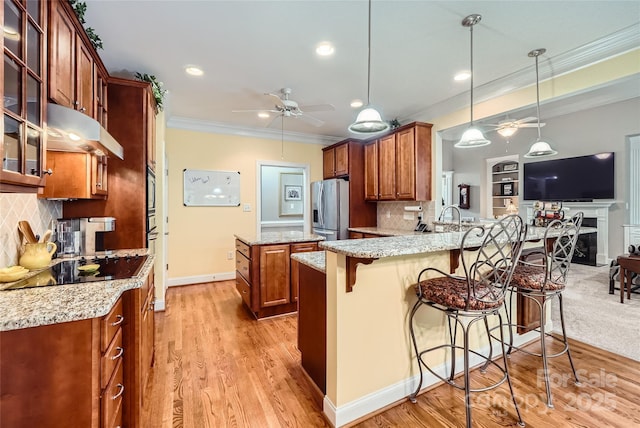 kitchen featuring a ceiling fan, stainless steel fridge with ice dispenser, ornamental molding, under cabinet range hood, and brown cabinets