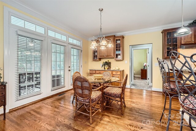 dining room featuring crown molding, light wood-style floors, and baseboards