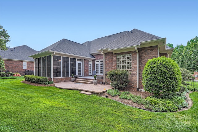 back of property with a patio area, a sunroom, brick siding, a lawn, and a shingled roof