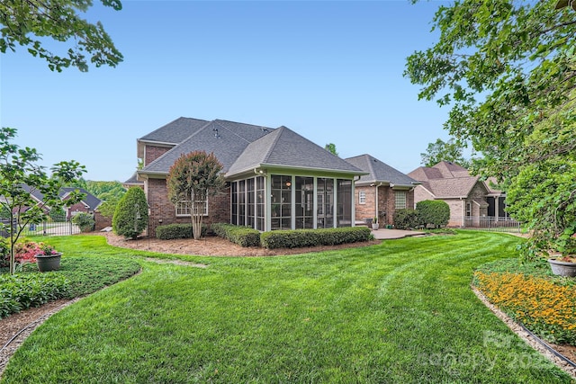 rear view of house featuring a sunroom, brick siding, and roof with shingles