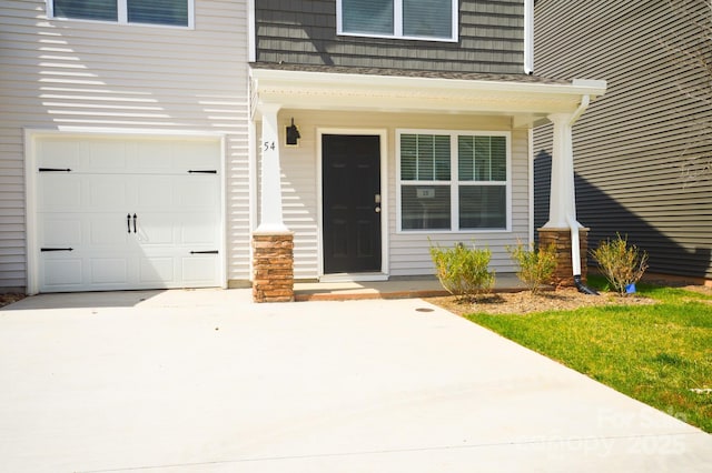 view of exterior entry featuring covered porch, concrete driveway, and an attached garage
