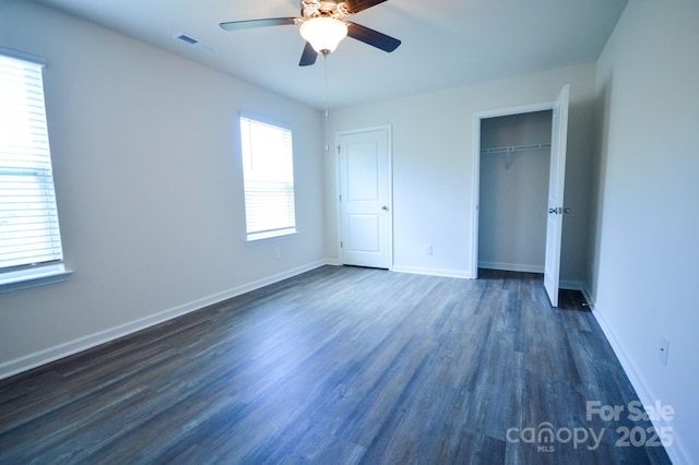 unfurnished bedroom with baseboards, a closet, visible vents, and dark wood-style floors