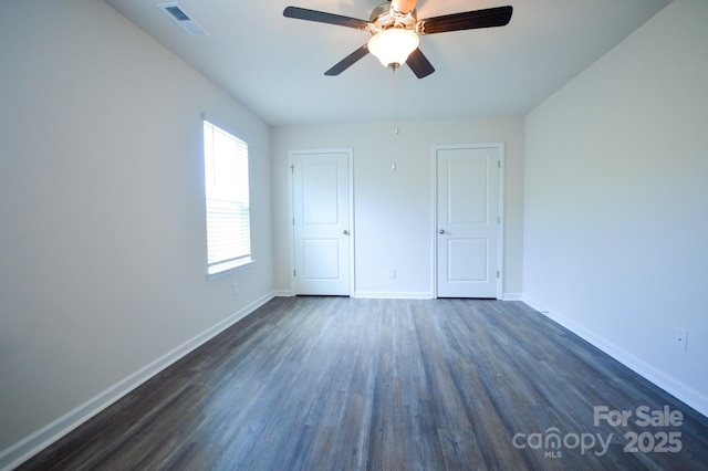 unfurnished bedroom with baseboards, dark wood-style flooring, ceiling fan, and visible vents