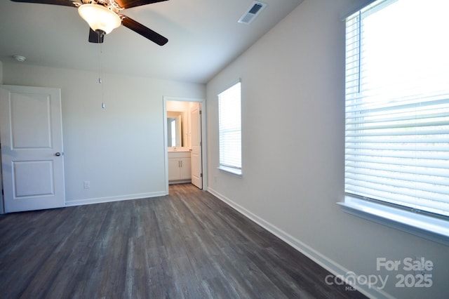 unfurnished bedroom featuring ensuite bathroom, visible vents, dark wood finished floors, ceiling fan, and baseboards