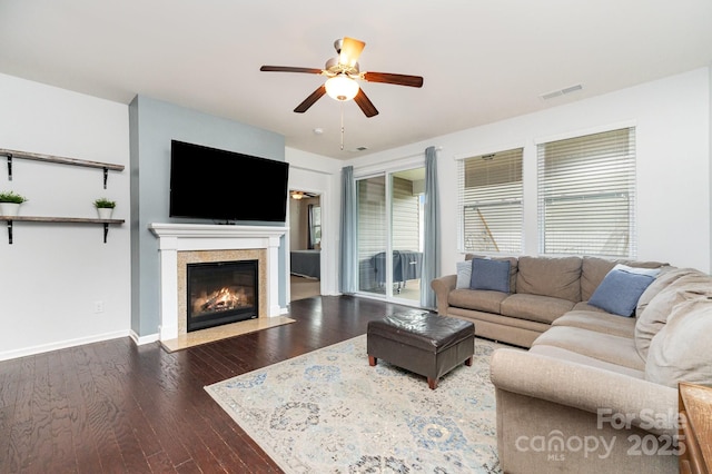 living area with a ceiling fan, visible vents, a fireplace with flush hearth, and dark wood-type flooring