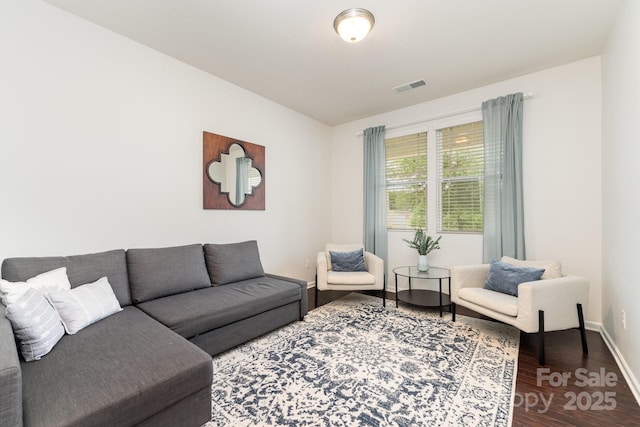 living area featuring visible vents, wood finished floors, and baseboards