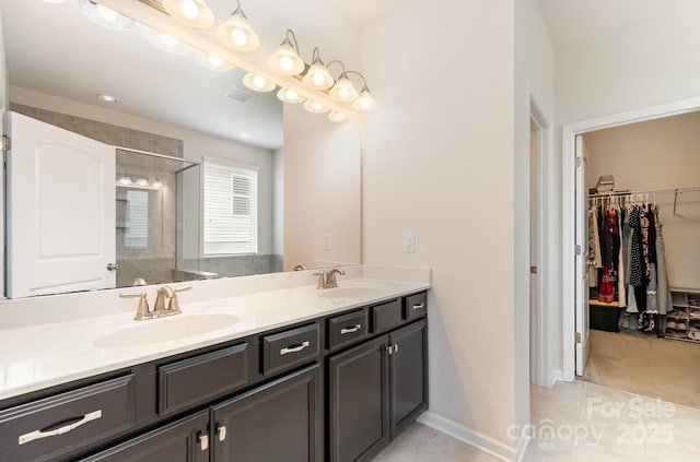 full bathroom featuring a sink, double vanity, tiled shower, and tile patterned floors