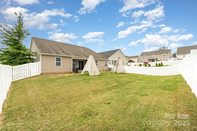back of house with a lawn and a fenced backyard