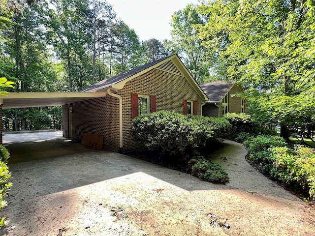 view of home's exterior with driveway, an attached carport, and brick siding