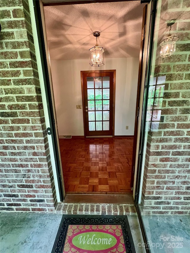 doorway to property with brick siding and visible vents