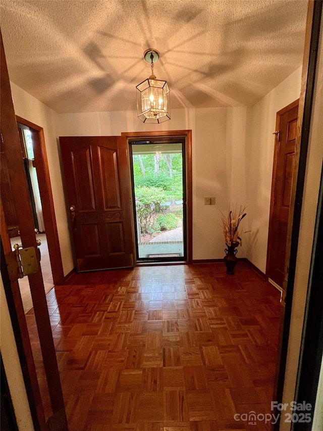 entryway featuring baseboards, a chandelier, and a textured ceiling