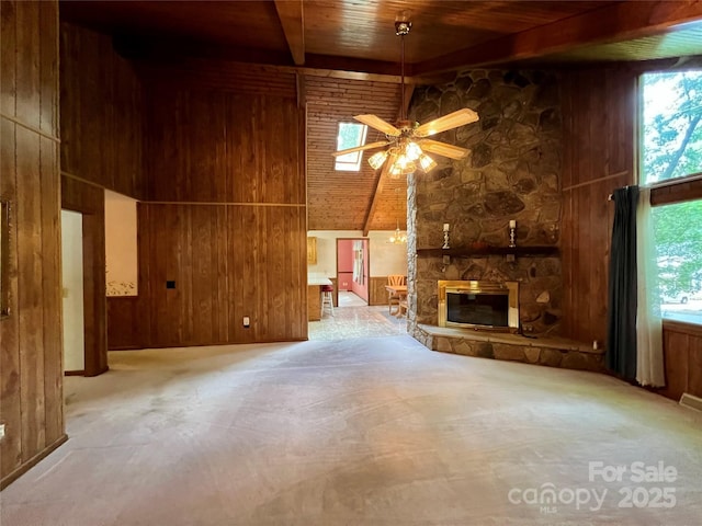 unfurnished living room with beamed ceiling, wood walls, high vaulted ceiling, and wood ceiling