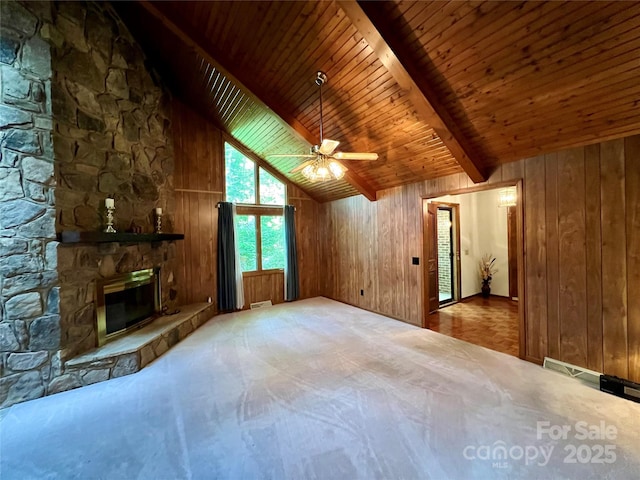 unfurnished living room featuring wooden walls, carpet flooring, beamed ceiling, and a ceiling fan