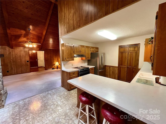kitchen with freestanding refrigerator, range hood, electric stove, light countertops, and wooden walls