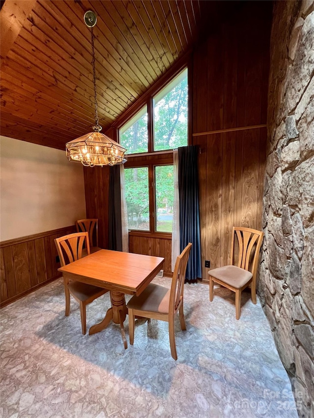dining space featuring lofted ceiling, a notable chandelier, wood ceiling, wood walls, and a wainscoted wall