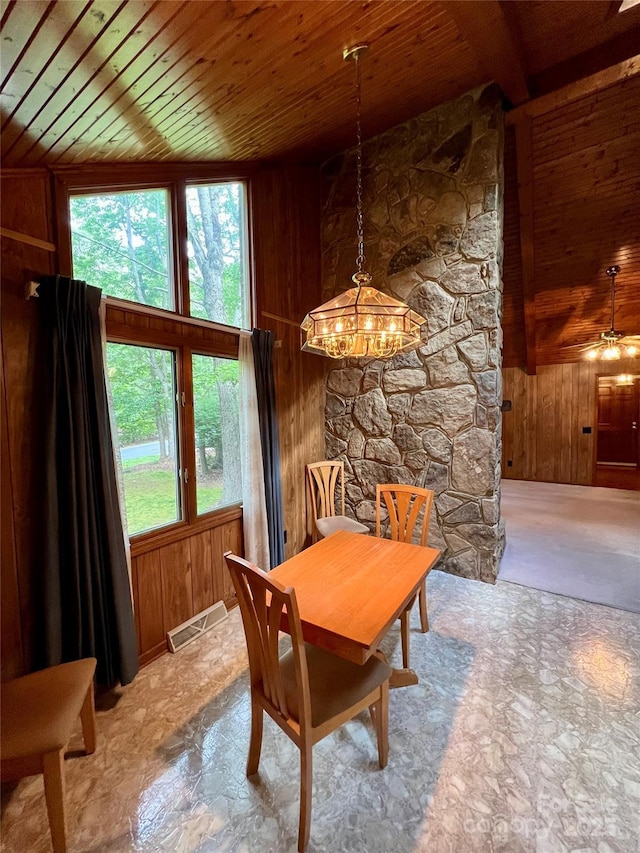 dining space with wood walls, an inviting chandelier, visible vents, and wooden ceiling