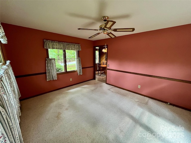 empty room featuring carpet flooring, baseboards, and a ceiling fan