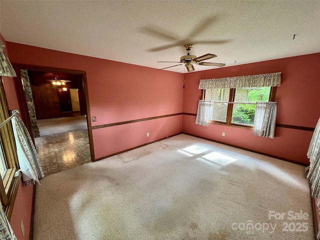 empty room featuring a textured ceiling, carpet floors, and a ceiling fan