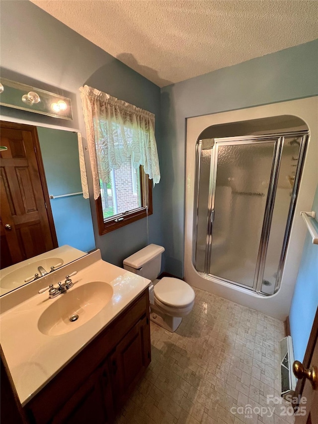 full bath with a shower stall, vanity, toilet, and a textured ceiling