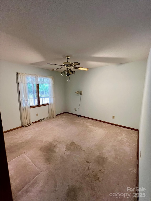 empty room with light colored carpet, visible vents, baseboards, and a ceiling fan