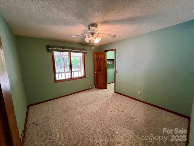 empty room featuring ceiling fan, a textured ceiling, carpet flooring, and visible vents