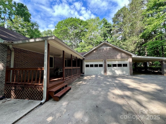 view of side of home with a porch, concrete driveway, and brick siding