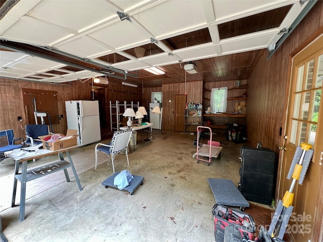 garage with freestanding refrigerator, wooden walls, and a garage door opener