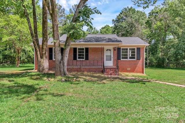 view of front of home featuring a front yard, covered porch, brick siding, and roof with shingles