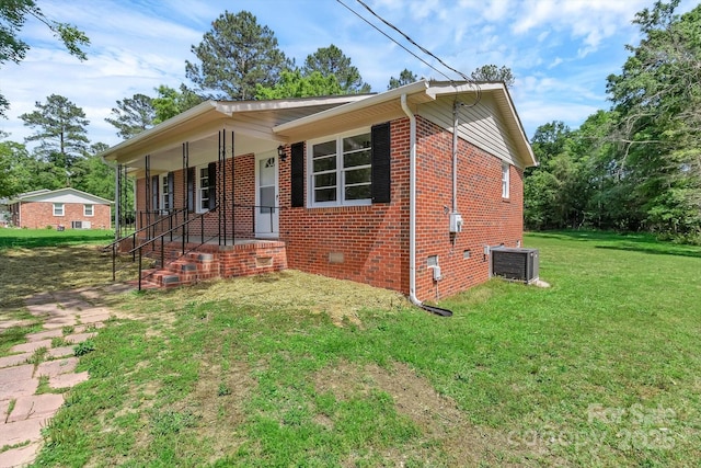view of front of home featuring a front yard, central AC unit, brick siding, and covered porch
