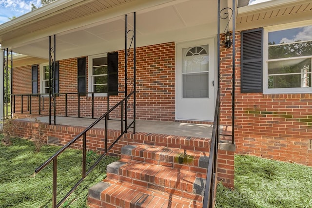 entrance to property featuring covered porch and brick siding