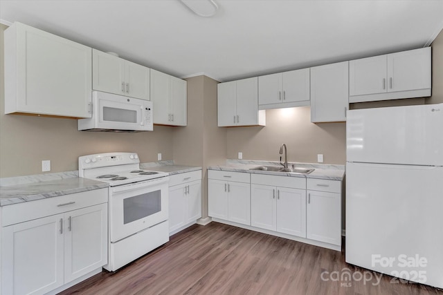 kitchen featuring white appliances, a sink, white cabinets, light wood finished floors, and light stone countertops