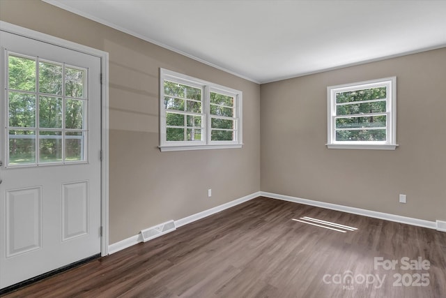 unfurnished room featuring baseboards, dark wood-style flooring, crown molding, and healthy amount of natural light