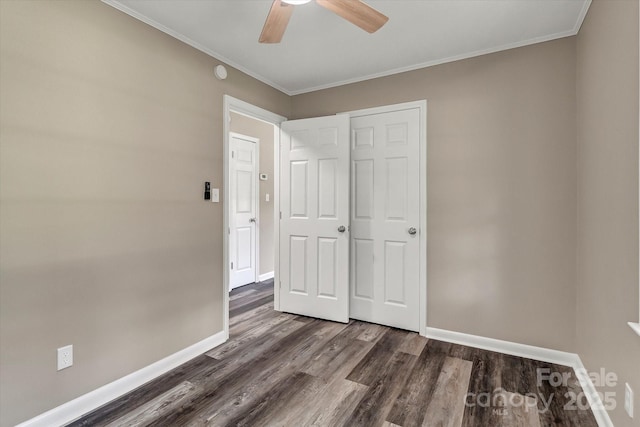 unfurnished bedroom with dark wood-type flooring, baseboards, ornamental molding, and ceiling fan