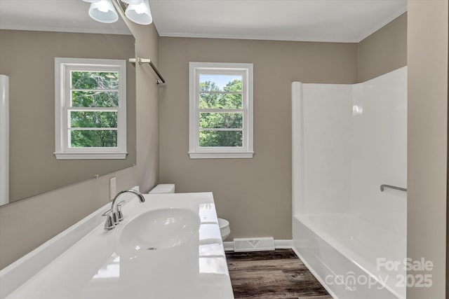 bathroom with toilet, healthy amount of natural light, vanity, and wood finished floors