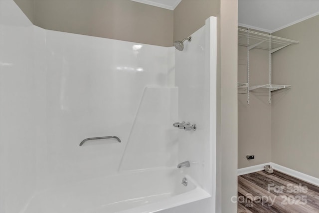 full bath with ornamental molding, wood finished floors, baseboards, and tub / shower combination