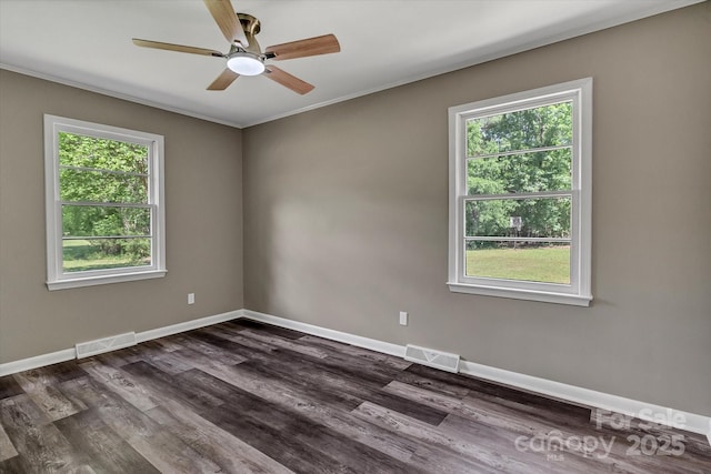 unfurnished room featuring healthy amount of natural light, a ceiling fan, dark wood finished floors, baseboards, and crown molding
