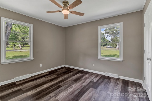 empty room featuring healthy amount of natural light, crown molding, dark wood-type flooring, a ceiling fan, and baseboards