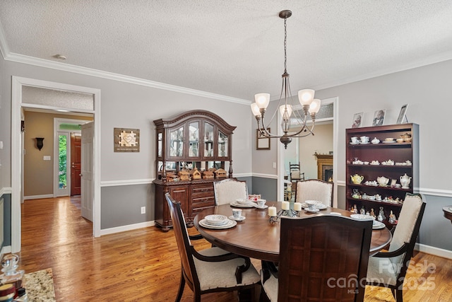 104 Belvedere Dr, Morganton, NC 28655 - dining area with light wood-style floors, a textured ceiling, a chandelier, crown molding, and baseboards