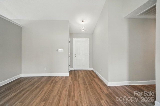 empty room with wood finished floors, baseboards, and vaulted ceiling