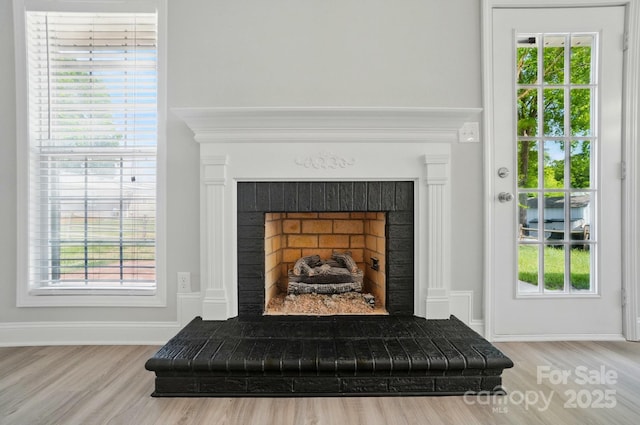 detailed view of wood finished floors, a fireplace, and baseboards