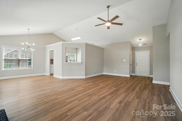 unfurnished living room with vaulted ceiling, healthy amount of natural light, a chandelier, wood finished floors, and ceiling fan