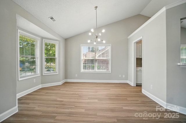 unfurnished dining area with vaulted ceiling, a chandelier, light wood-style floors, and baseboards